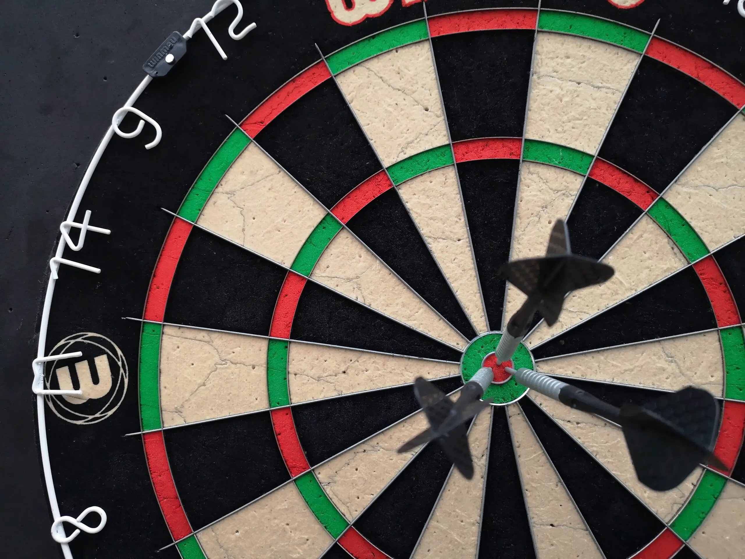 A close up shot of a dartboard with darts on the bullseye